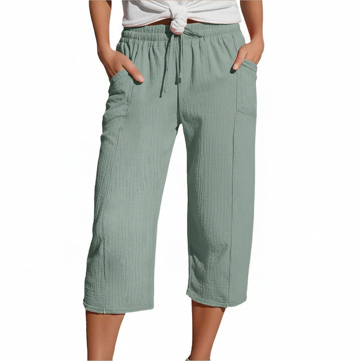 Model in lichtgroene driekwart broek met elastische taille en zijzakken, staand met handen in zakken.