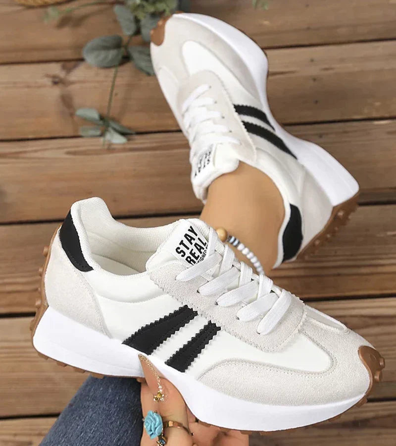 Zijkant van trendy dames platform sneakers met opvallende strepen en dikke comfortabele zool.
