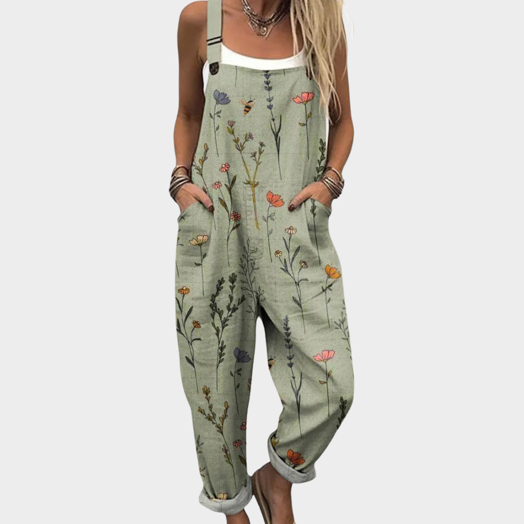 Vrouwelijke groene jumpsuit met bloemenprint en wijde pijpen gedragen met een wit hemdje
