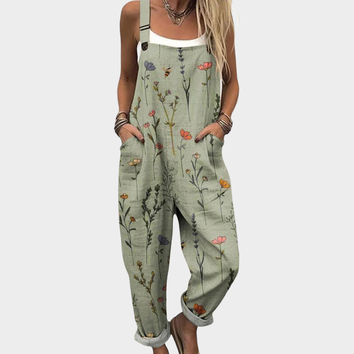 Vrouwelijke groene jumpsuit met bloemenprint en wijde pijpen gedragen met een wit hemdje