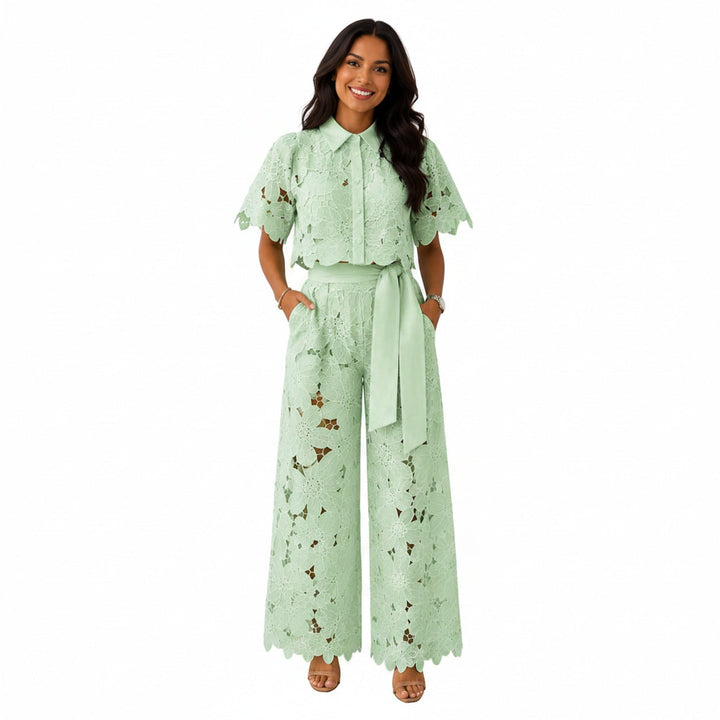 Model draagt een lichtgroene kanten crop top en wijde broek set met strikceintuur