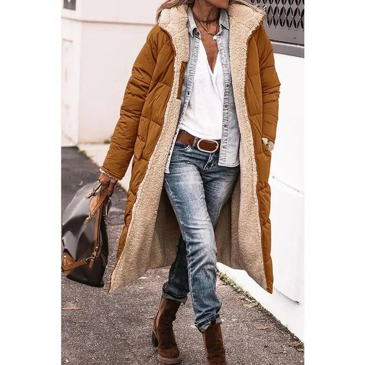 Zwarte lange dames pufferjas met capuchon, tijdloos en warm. Essentiële outwear voor de winter.