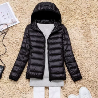 Vrouw draagt modieuze lichtgewicht gewatteerde damesjas met capuchon. Warme en comfortabele casual winterjas.