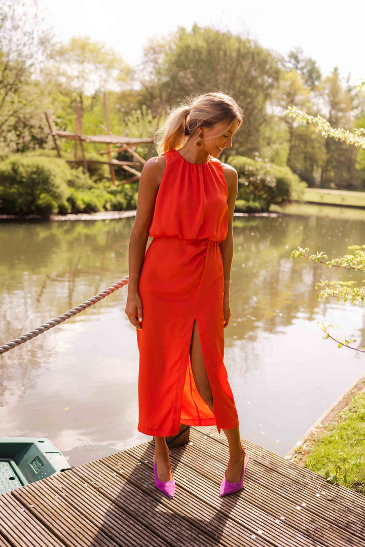 Rode mouwloze dames midi jurk met elegante halskraag en sensuele beenslip. Perfect als avondjurk of feestjurk.