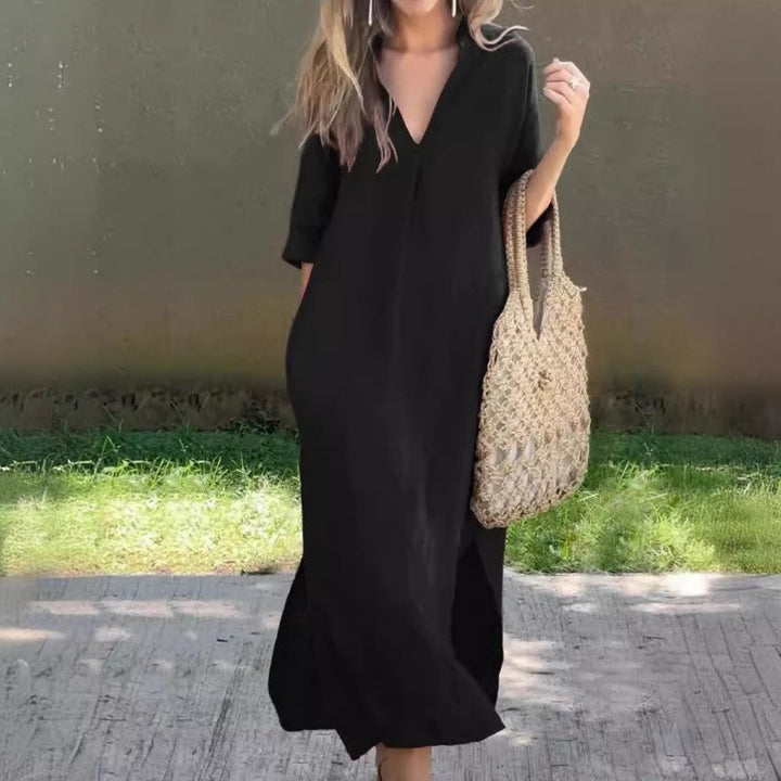 Model in luchtige Soraya katoenlinnen zomerjurk met V-hals, kuitsplit. Perfect voor strand of een casual avond.