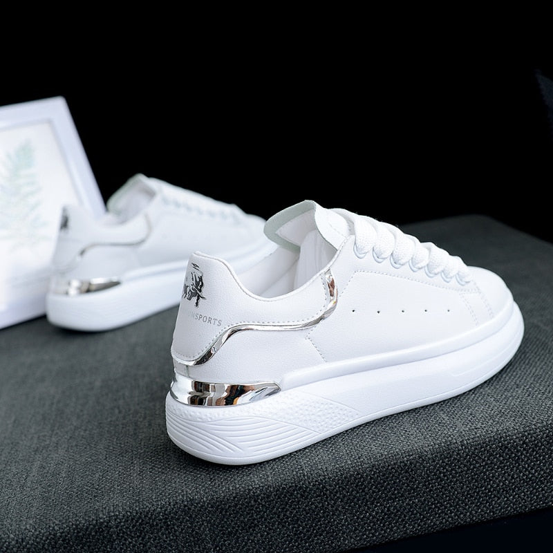 Vrouw draagt TrienkesSneaks: stijlvolle, comfortabele witte en zilveren damessneakers voor een casual look.