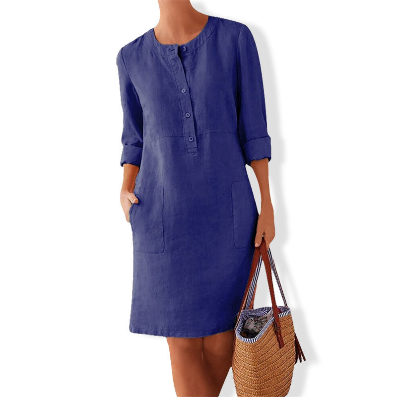 Vrouw draagt Adelle zomerjurk, zittend, comfortabel en casual. Ideale midi jurk voor ontspannen zomerse momenten.