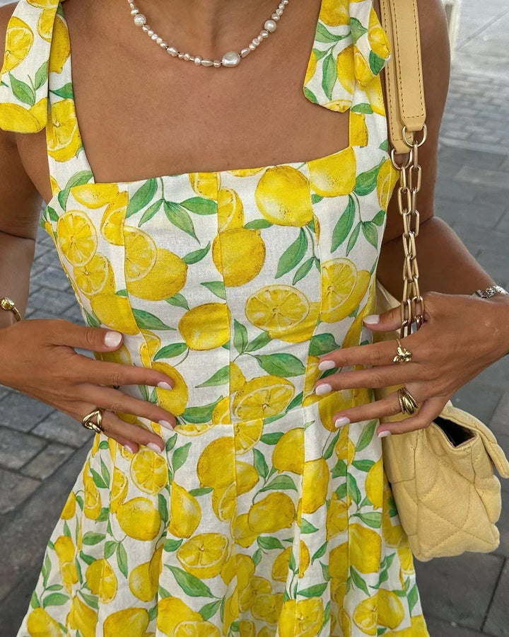 Detail van een frisse, gele citroenprint op een lichte dames zomerjurk. Vrolijke vrouwenmode.