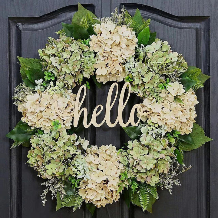 Groene hortensia krans met hallo bord aan een donkere voordeur