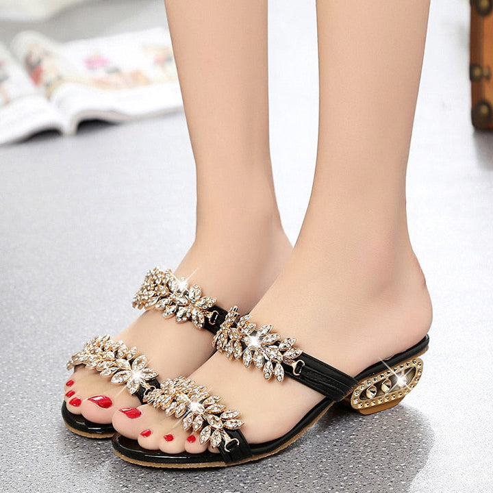 Vrouwenvoeten dragen modieuze glitter slippers. Deze comfortabele elegante platte schoenen zijn perfect voor zomerstijl.