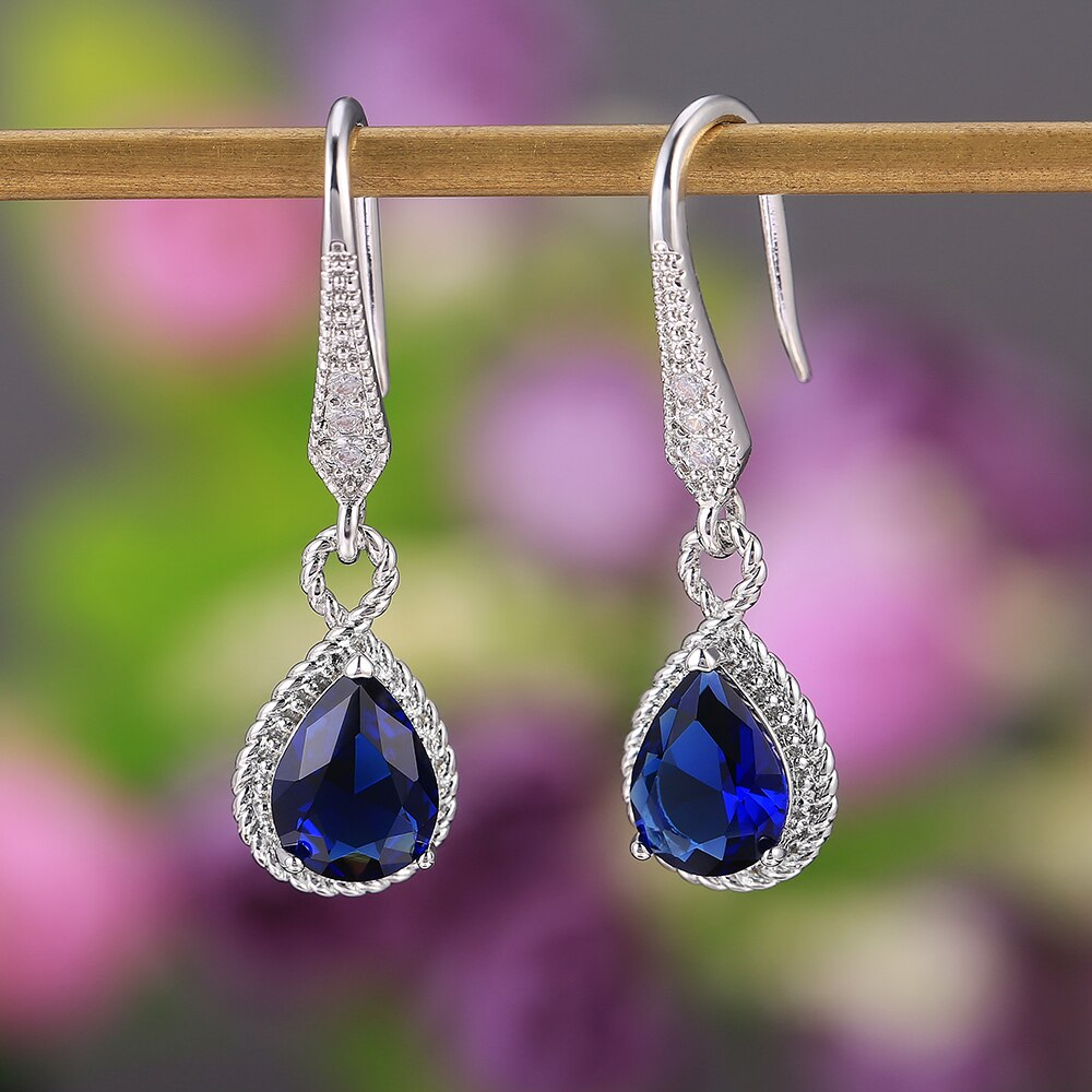 Close-up van schitterende zilveren damesoorbellen met heldere blauwe zirkoon steen.