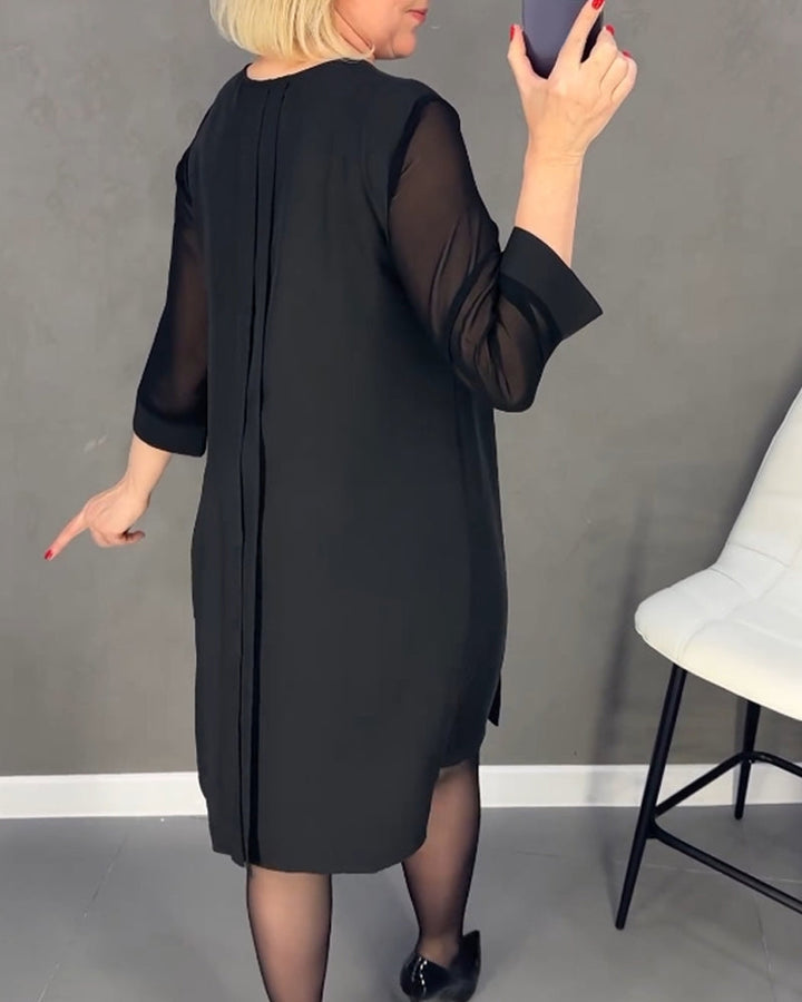 Zwarte elegante shiftjurk met subtiele meshdetails aan de mouwen. Een modieuze en veelzijdige keuze voor dames.