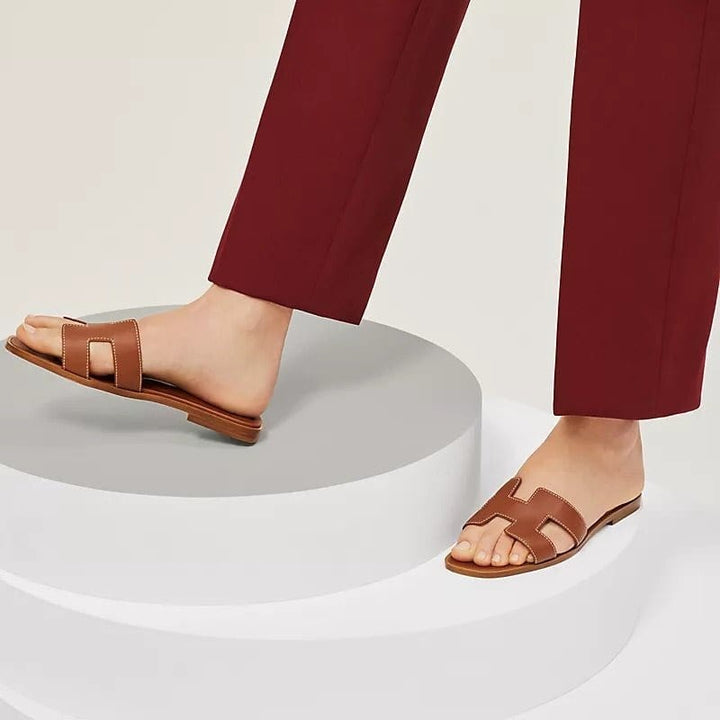 Elegante platte dames sandalen in bruin gedragen op een podium
