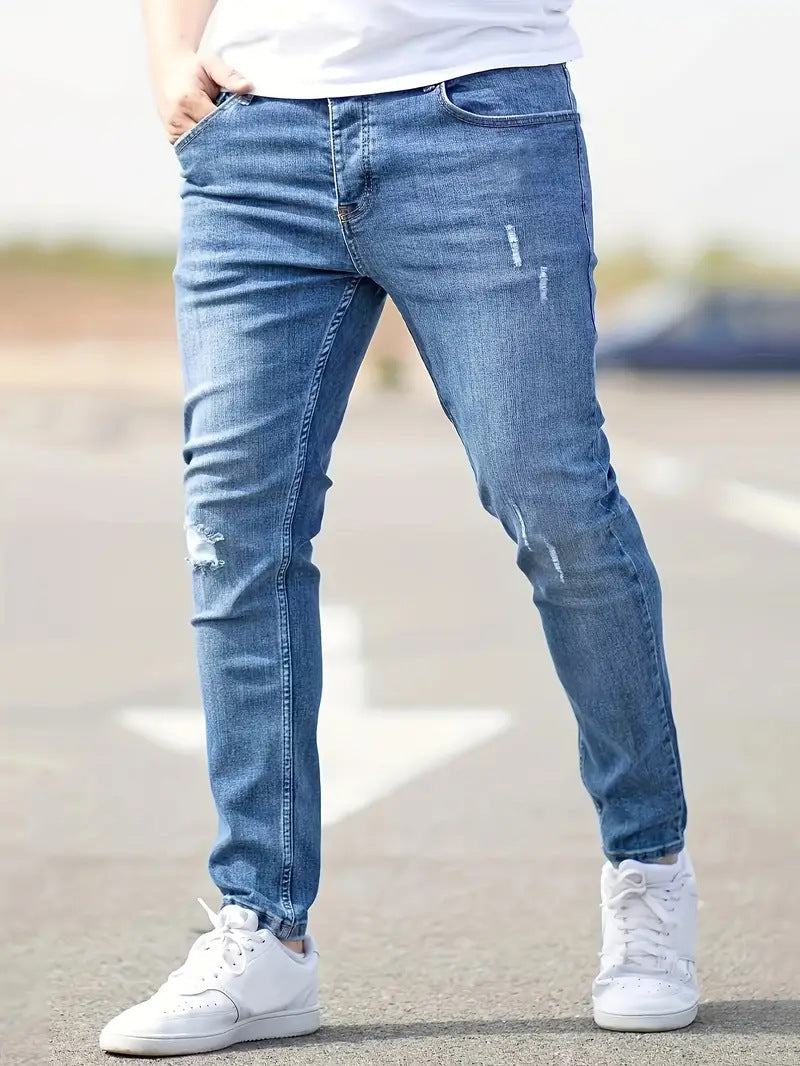 Man draagt blauwe skinny heren spijkerbroek met witte sneakers