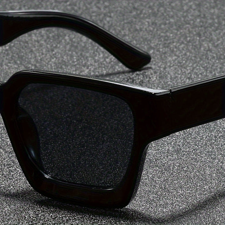 Detailopname van het glanzende zwarte montuur en de donkere lens van de retro zonnebril.