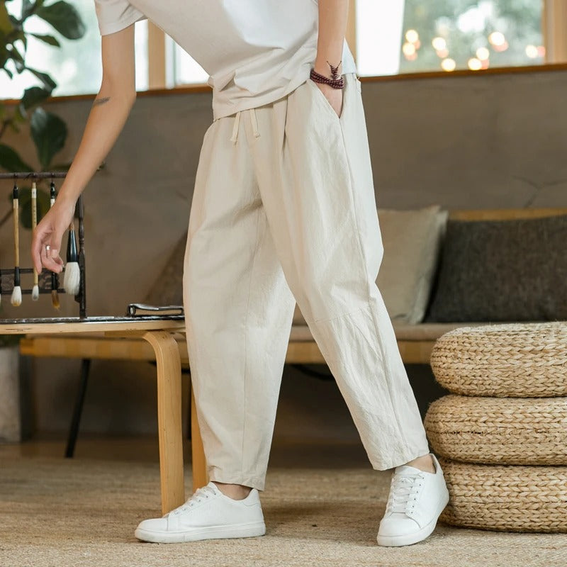 Man draagt een luchtige beige herenbroek met witte schoenen