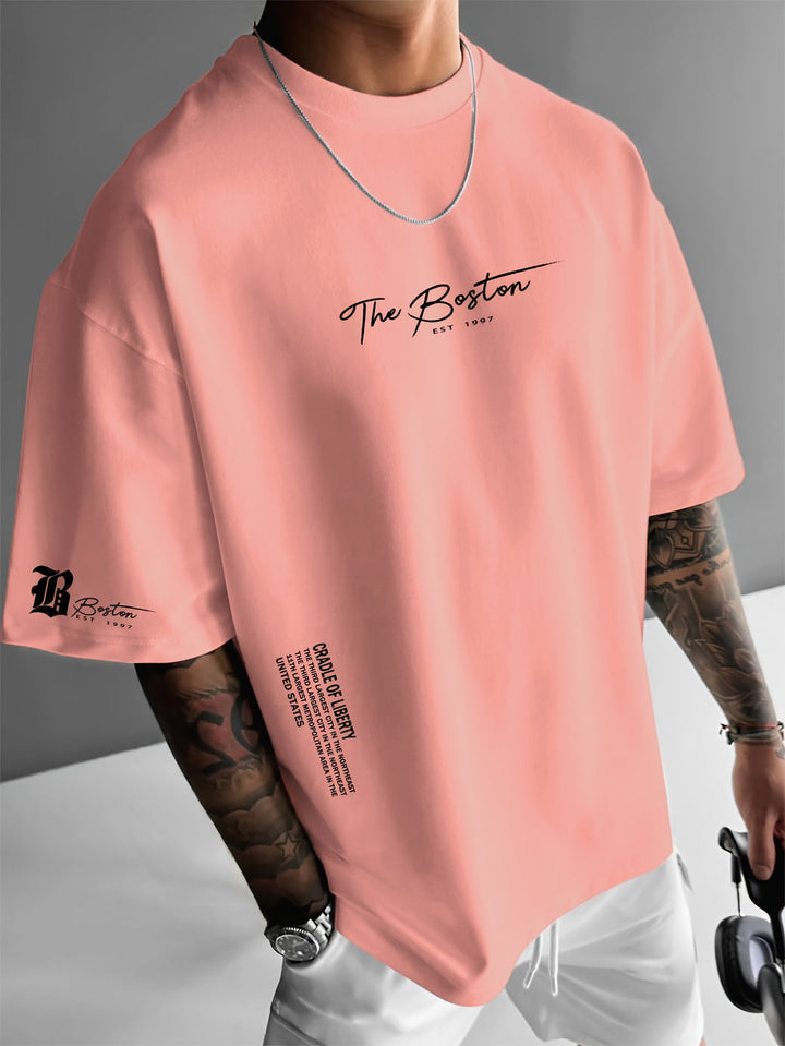 Man draagt casual heren T-shirt met trendy slogan print, losse pasvorm, ideaal voor zomerse dagen en streetwear.