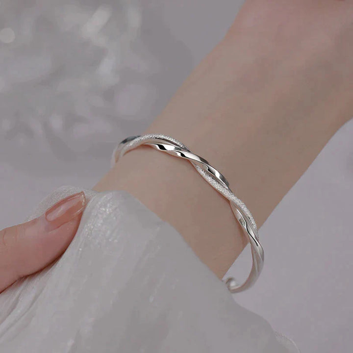 Gedraaide zilveren damesarmband met elegante twist, een stijlvol sieraad.