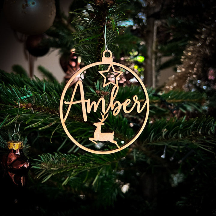 Detail van een gepersonaliseerd houten kerstornament met naam en delicate gravering.