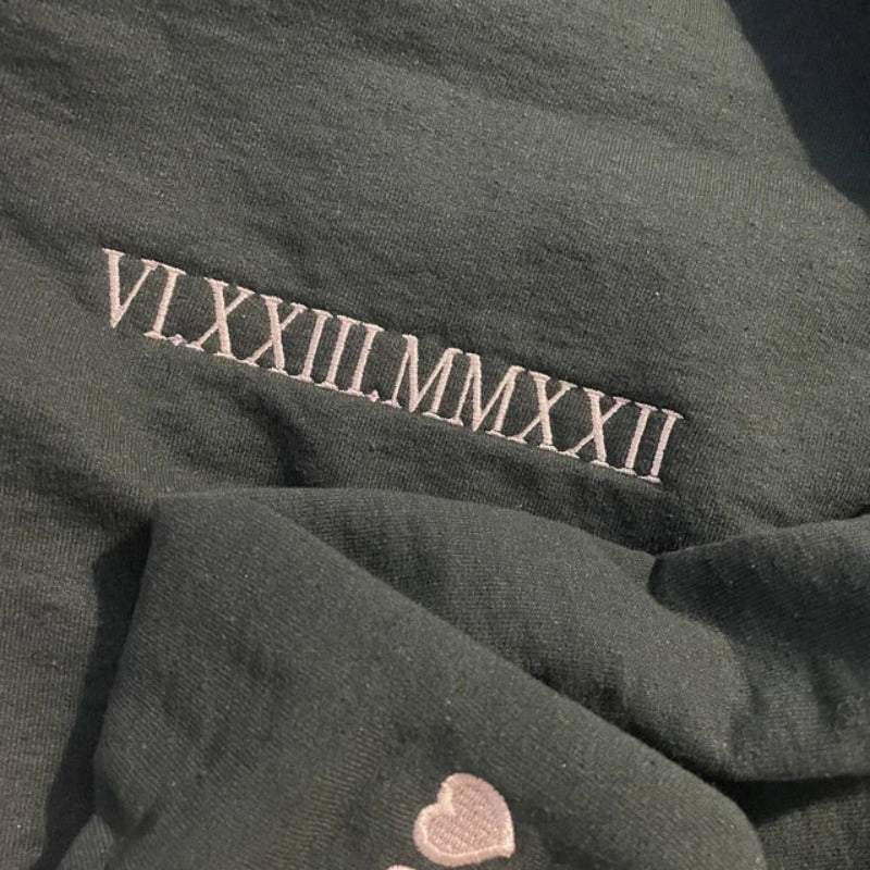 Detailopname van het fijn geborduurde Romeinse cijfer ontwerp op deze unieke koppel hoodie.