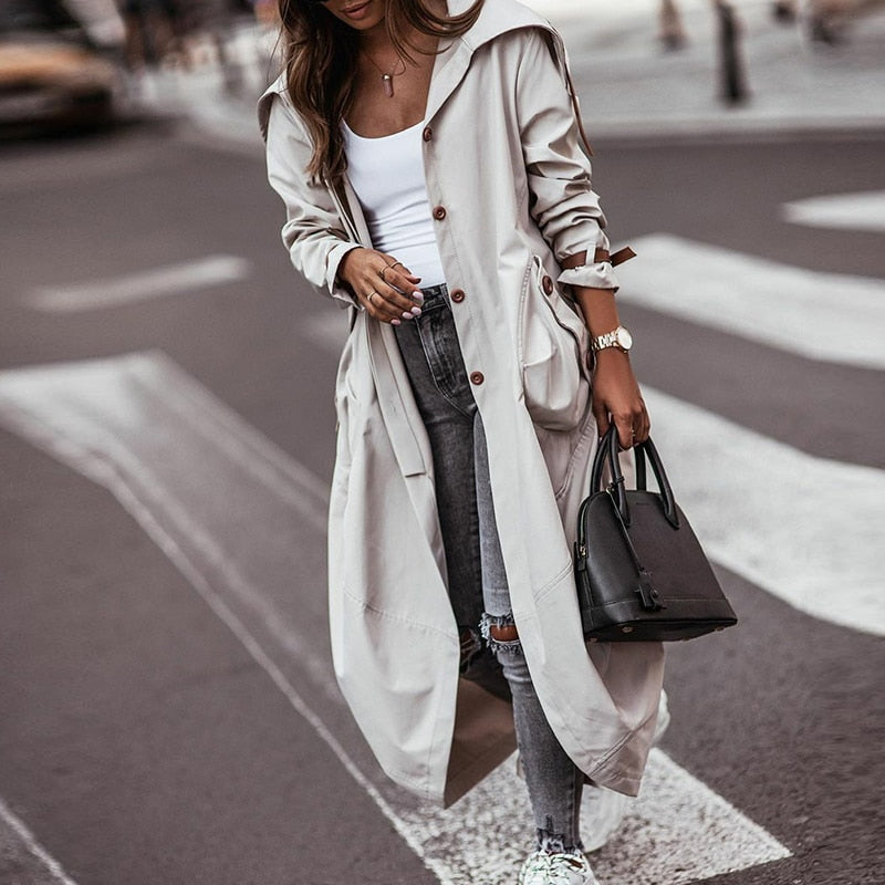 Grijze lange dames trenchcoat met praktische zakken, ideaal voor een tijdloze en elegante look.