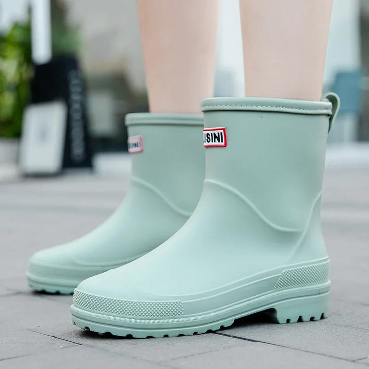Vrouw draagt AquaStride 2.0 halve-hoge regenlaarzen tijdens wandeling op een regendag.