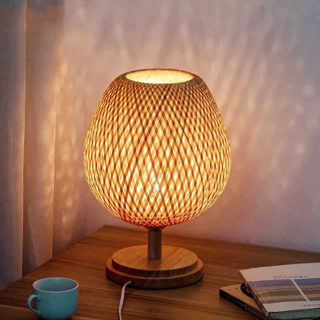 Sfeervolle bamboe tafellamp op nachtkastje. Creëert rustieke verlichting in de slaapkamer. Natuurlijke materialen.