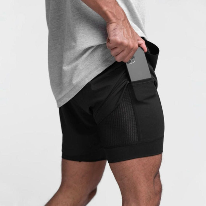 Man draagt comfortabele heren 2-in-1 trainingsshorts. Geschikt voor fitness, hardlopen en outdoor sport.