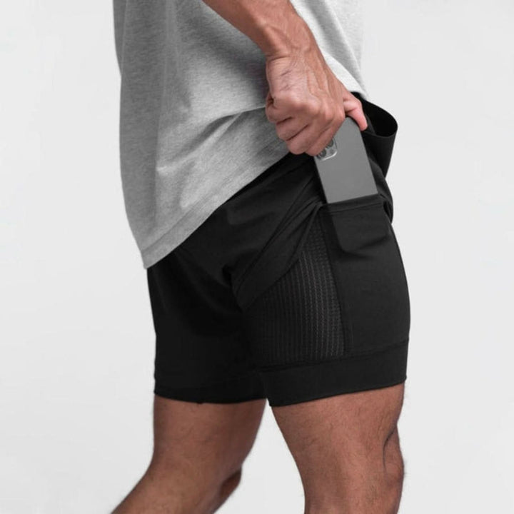 Man draagt comfortabele heren 2-in-1 trainingsshorts. Geschikt voor fitness, hardlopen en outdoor sport.