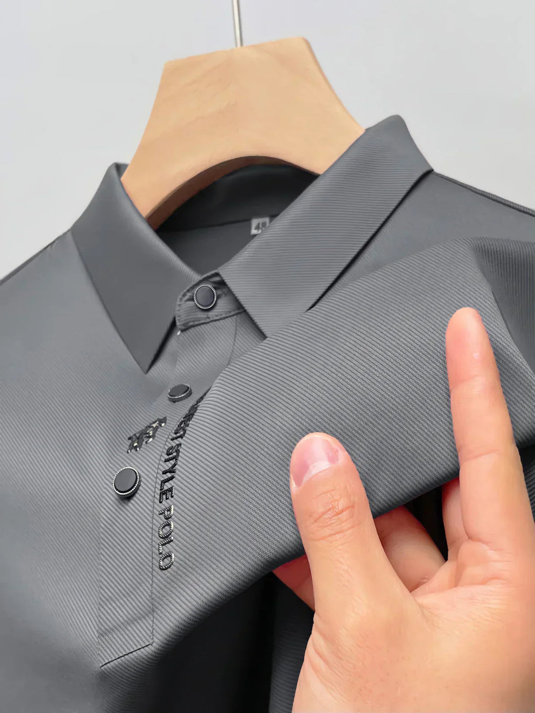Man draagt comfortabel grijs strijkvrij herenpoloshirt, perfect voor een casual zakelijke outfit.