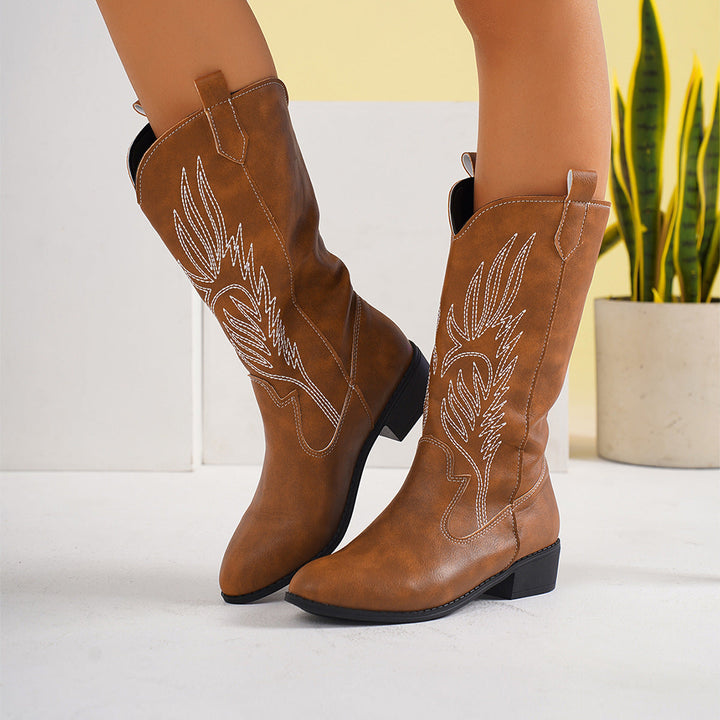 Hoge leren western laarzen voor dames in een herfstlandschap. Perfecte modieuze damesschoenen.
