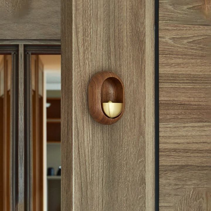 Detailfoto van de ambachtelijke houten deurgong; toont de fijne afwerking en glanzende messing sfeerbel.