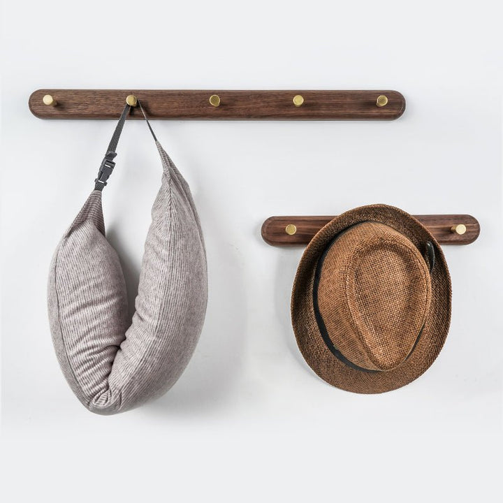 Houten wandkapstok met messing haken, ideaal voor een moderne hal of garderobe.