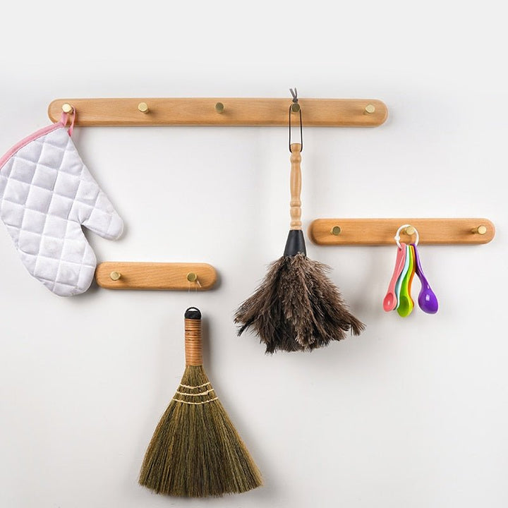 Minimalistische houten kapstok met luxe messing haken, perfect voor jassen en accessoires.