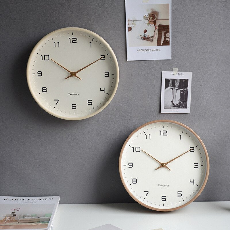 Twee Scandinavische houten wandklokken in bruin en crème aan een grijze muur