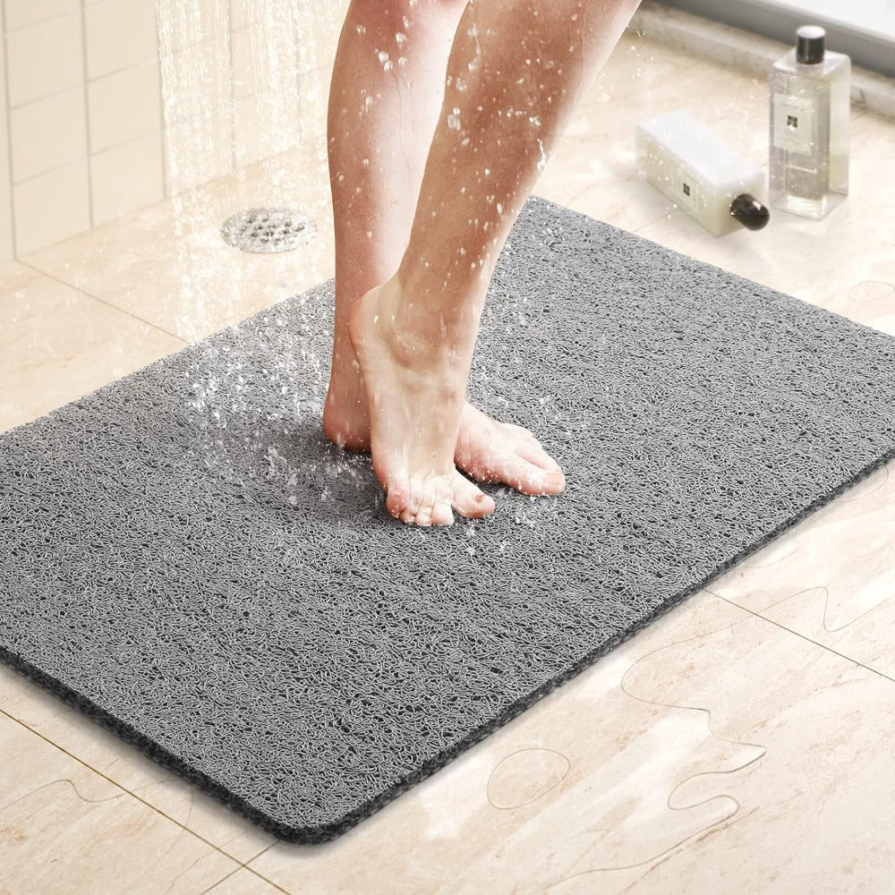 Vrouwenvoeten op een grijze anti-slip douchemat onder stromend water