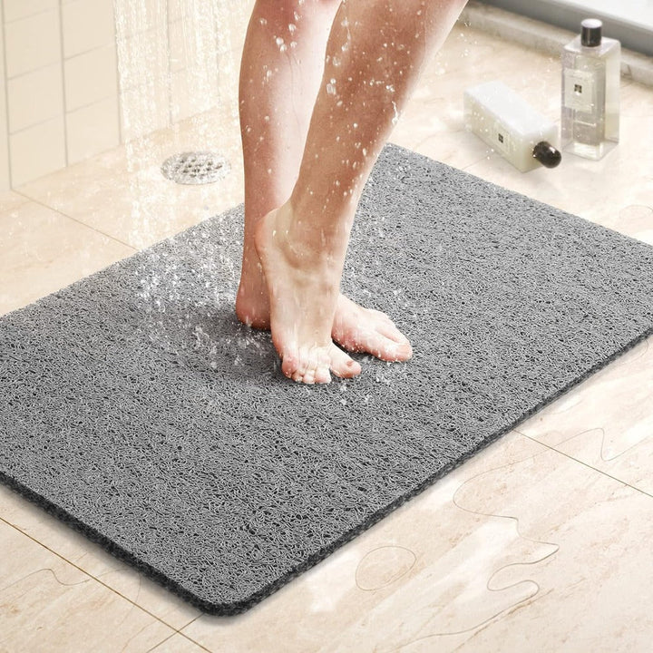 Vrouwenvoeten op een grijze anti-slip douchemat onder stromend water
