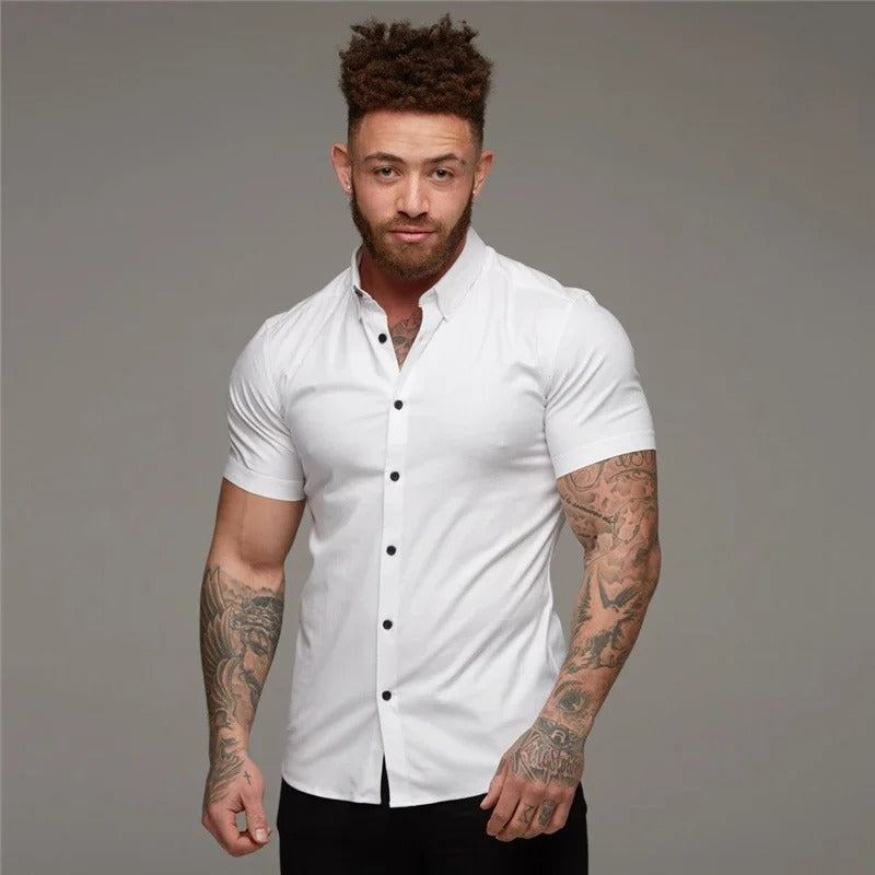 Mannelijk model draagt een wit, elegant heren overhemd met korte mouwen, ideaal voor een frisse zomerse look.