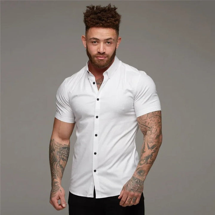 Mannelijk model draagt een wit, elegant heren overhemd met korte mouwen, ideaal voor een frisse zomerse look.