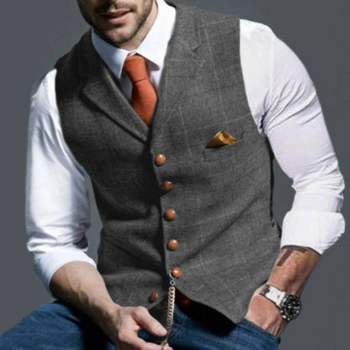 Donkergrijs geruit herenvest, ideaal voor een gelaagde, moderne look, met wit overhemd en oranje stropdas.