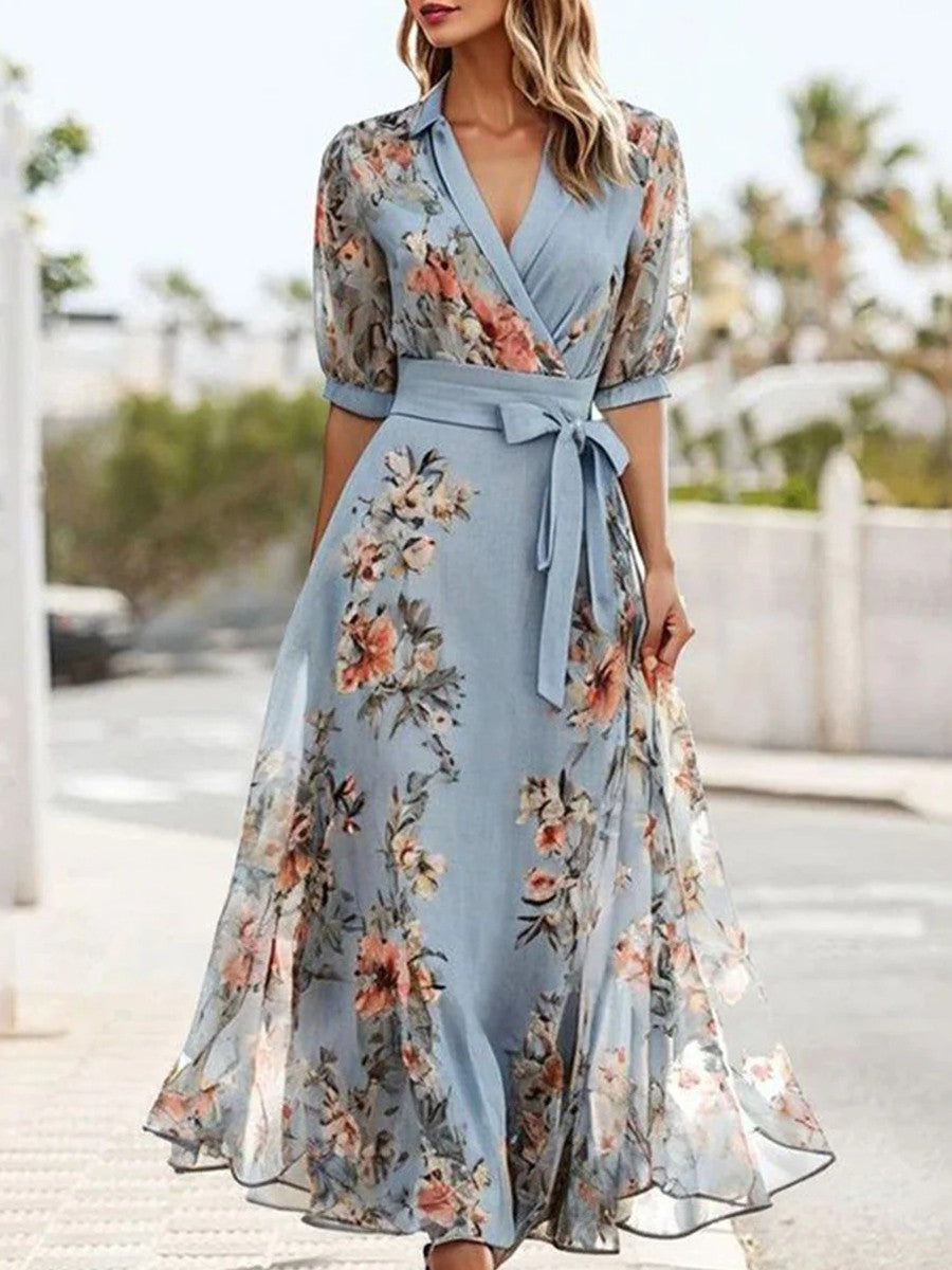 Lichtblauwe dames maxi jurk met bloemenprint, wikkelstijl en elegante v-hals. Perfecte zomerjurk.