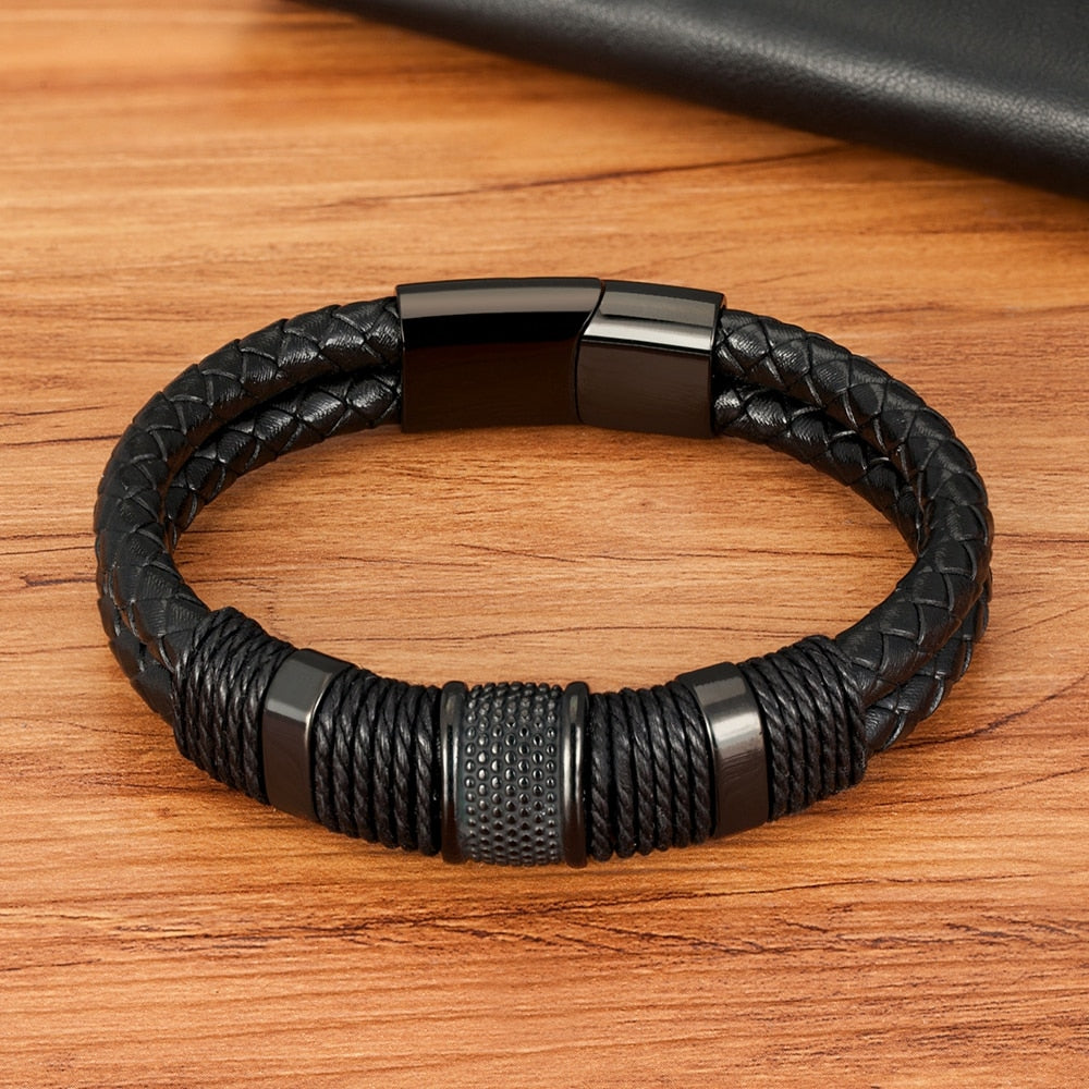 Assortiment gevlochten herenarmbanden in zwart, goud en grijs, met magnetische sluitingen, samen gepresenteerd.