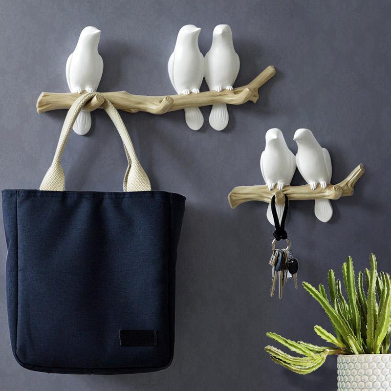 Set van twee witte vogels wandkapstokken met twee en vier haken, versierd met een tas en sleutels.
