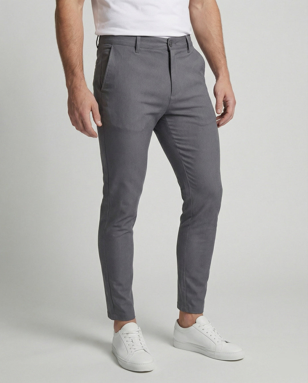 Man draagt grijze slim fit chino herenbroek met witte sneakers