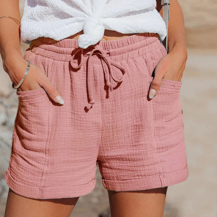 Model draagt blauwe loose fit dames shorts met elastische taille, ideaal als strandshorts en zomerkleding.