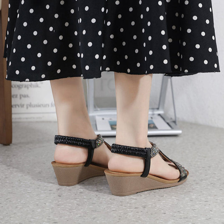 Moderne zwarte damessandalen met een hoge wedge hak en subtiele strass versiering.