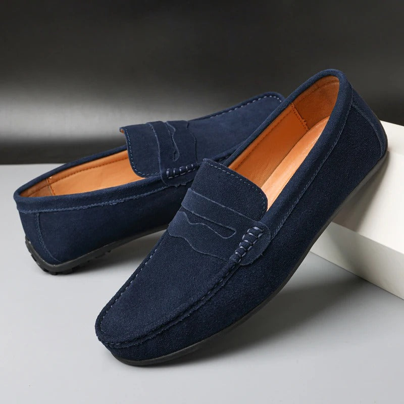 Marineblauwe heren loafers van zacht materiaal op een witte ondergrond