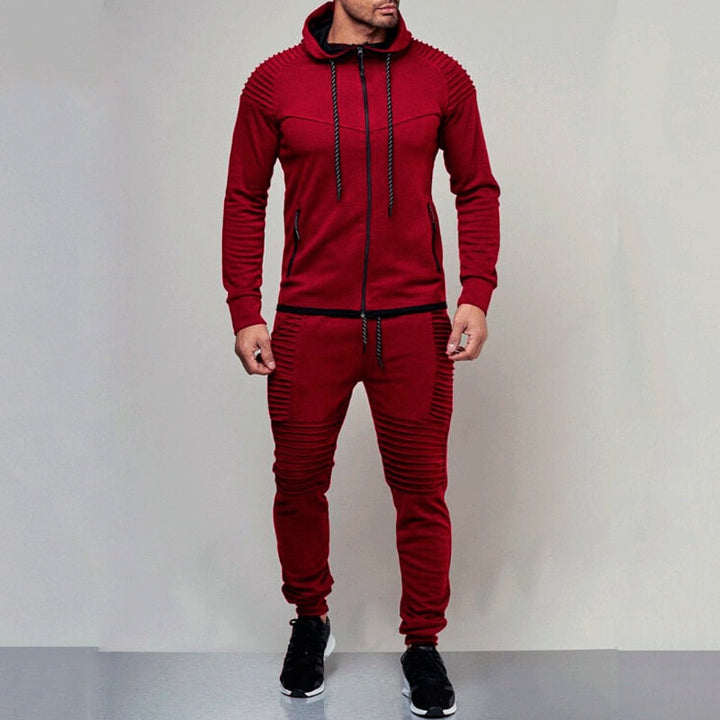 Man draagt comfortabel heren trainingspak met hoodie. Geschikt als sportkleding of modieuze casual outfit.