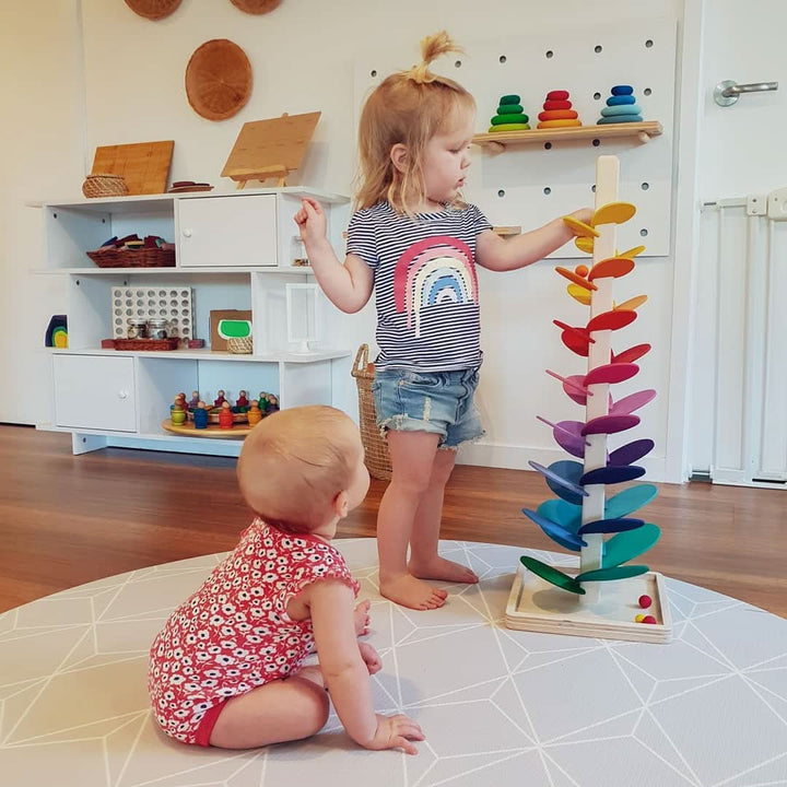 Jonge kind speelt met de grote houten klankboom in een lichte speelkamer