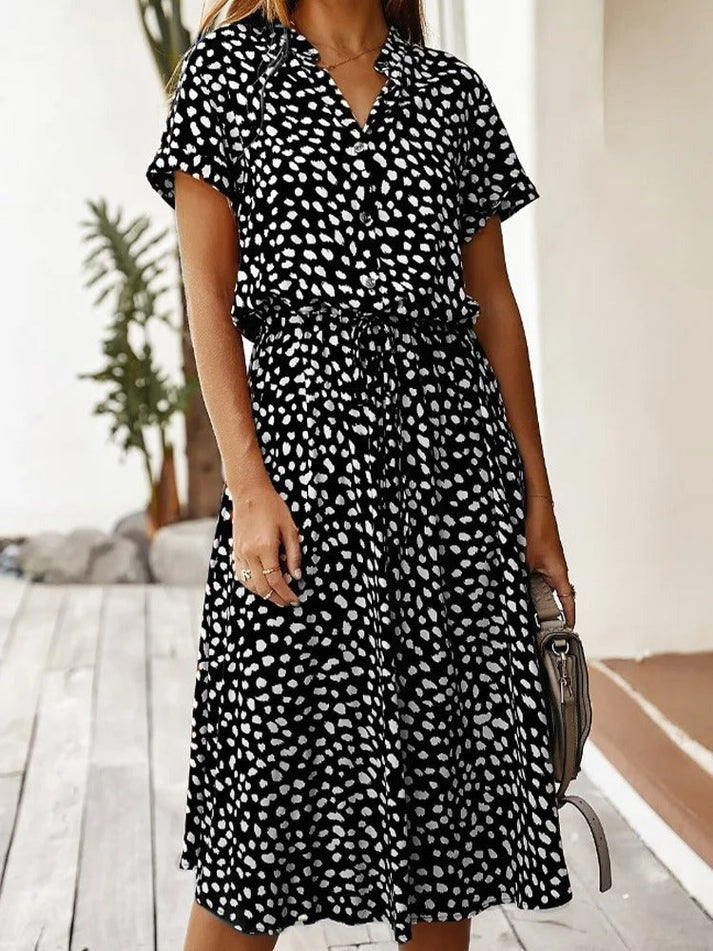 Vrouw draagt een zwarte midi blousejurk met print en stijlvolle details
